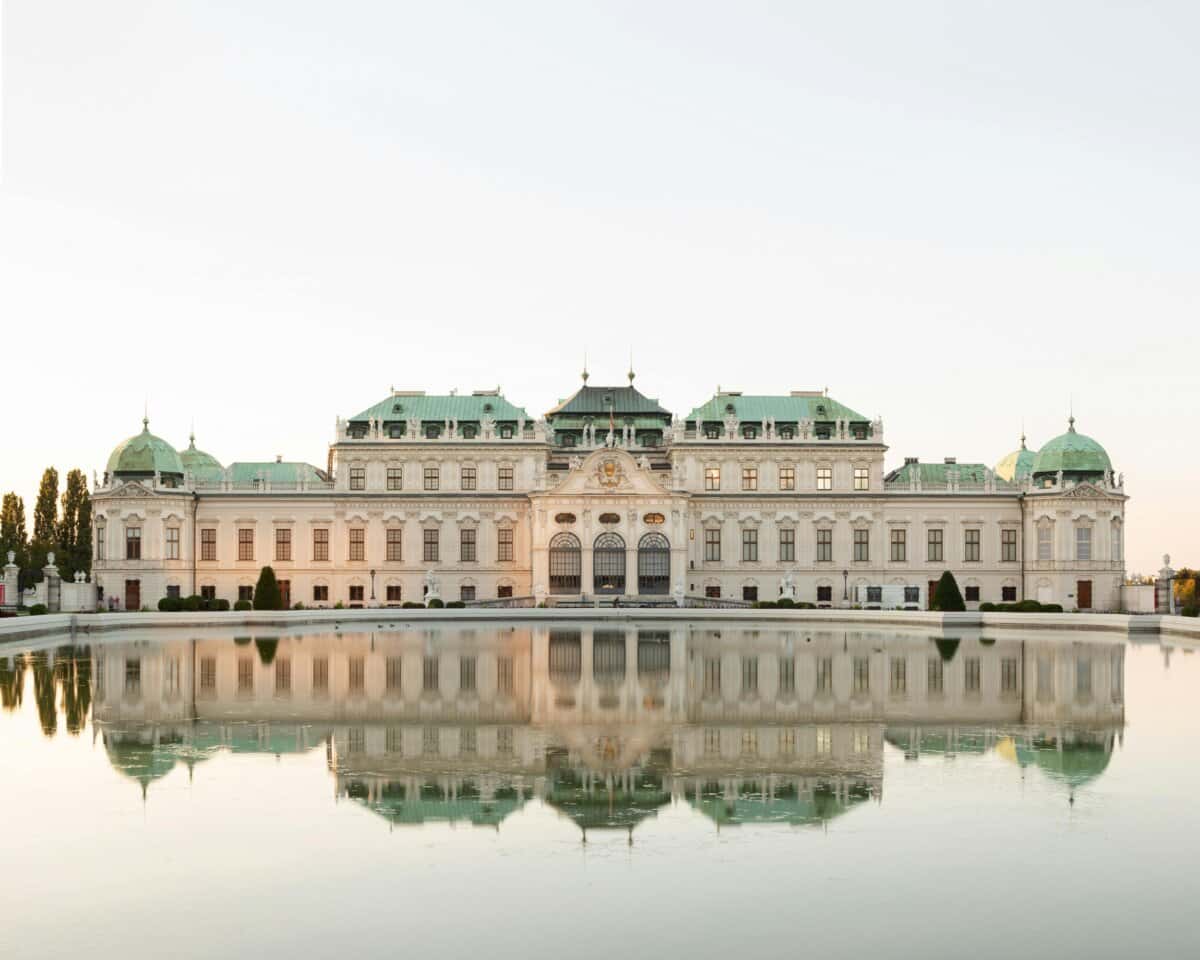 Historic palace reflected in calm water under clear sky.